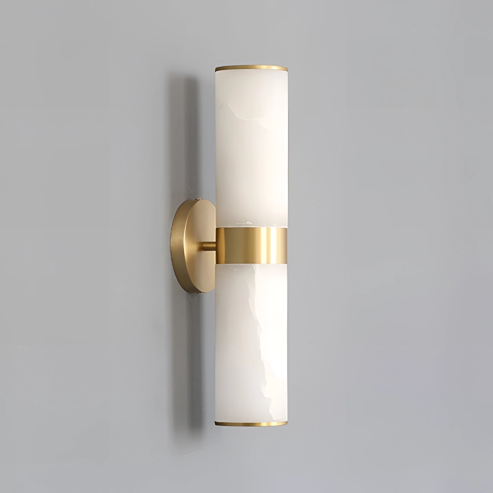 Gold bathroom sconce with a cylindrical frosted glass shade mounted on a wall, featuring a sleek metal design.