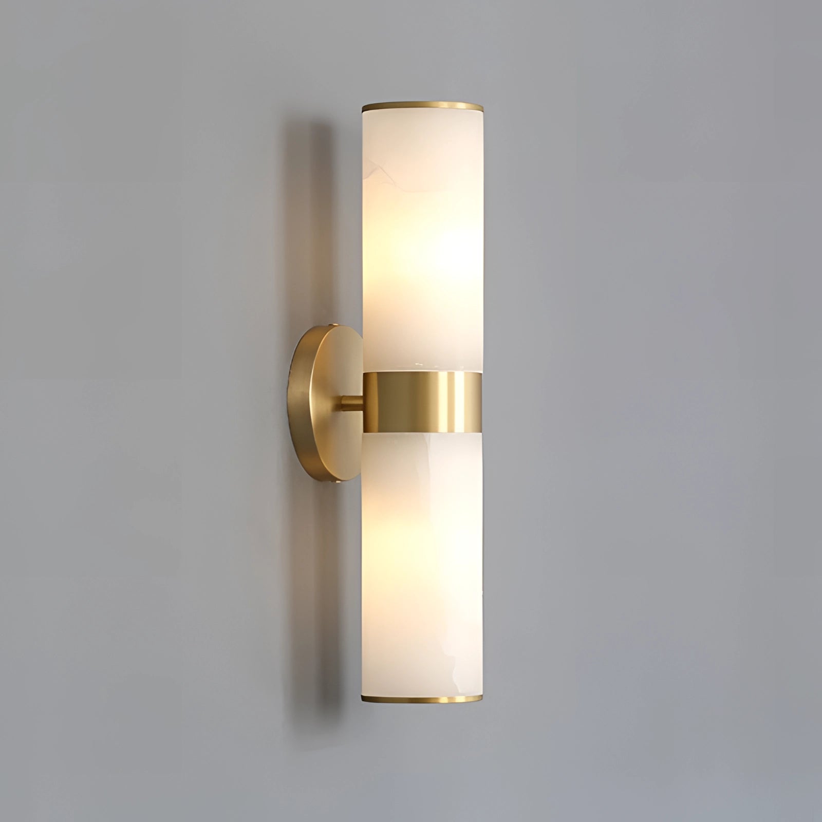 Gold bathroom sconce with a cylindrical frosted glass design mounted on the wall, providing elegant lighting to the space.