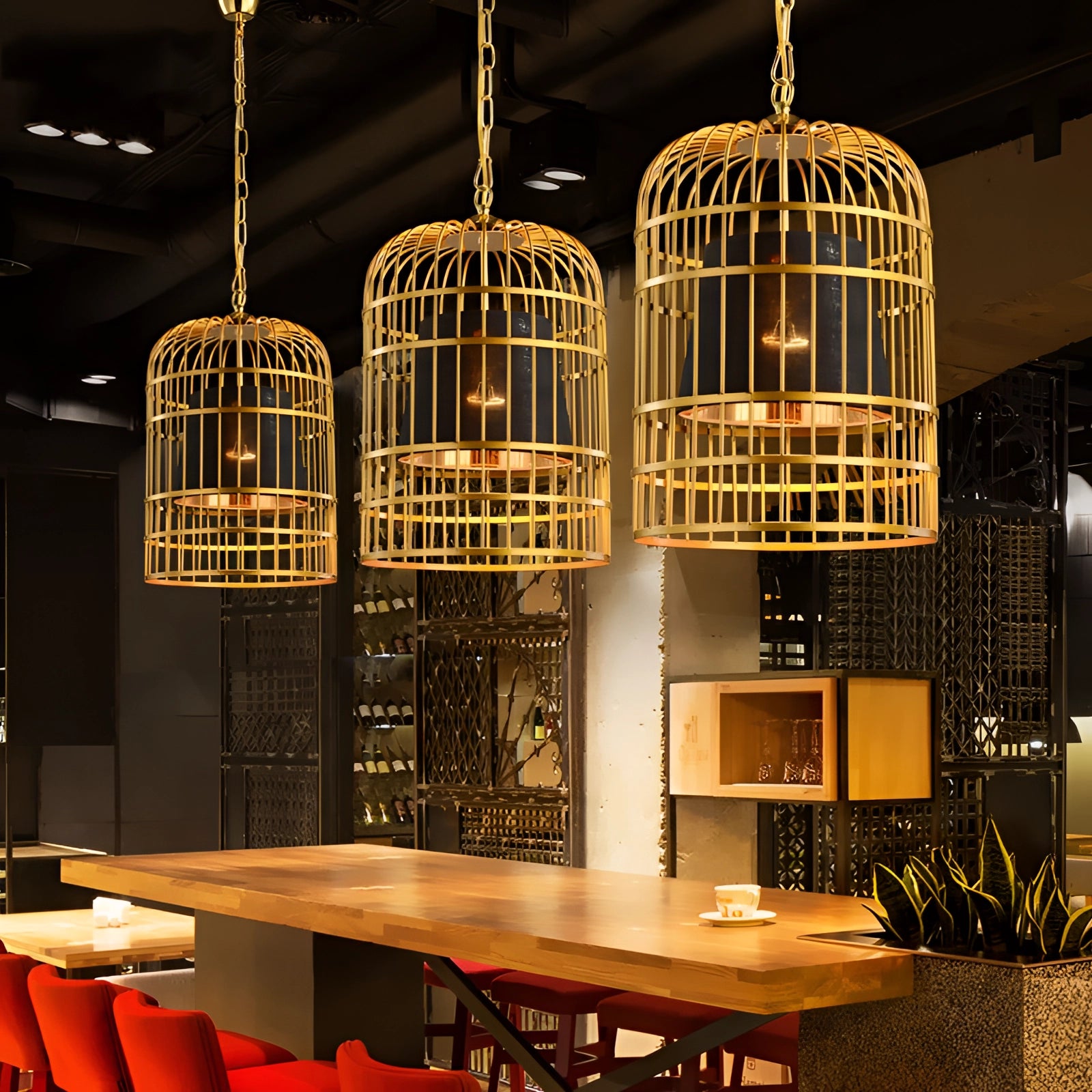 Gold birdcage chandelier hanging above a dining table with chairs, surrounded by modern interior design elements, including wooden furniture and a decorative plant.