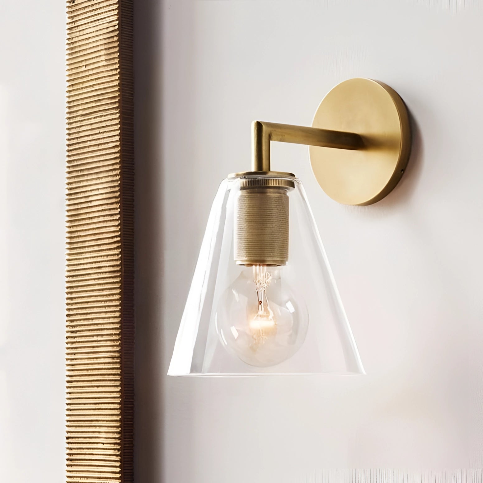 Gold brass wall sconce with geometric glass design, featuring a vintage bulb and industrial minimal aesthetic, mounted on a wooden shelf.