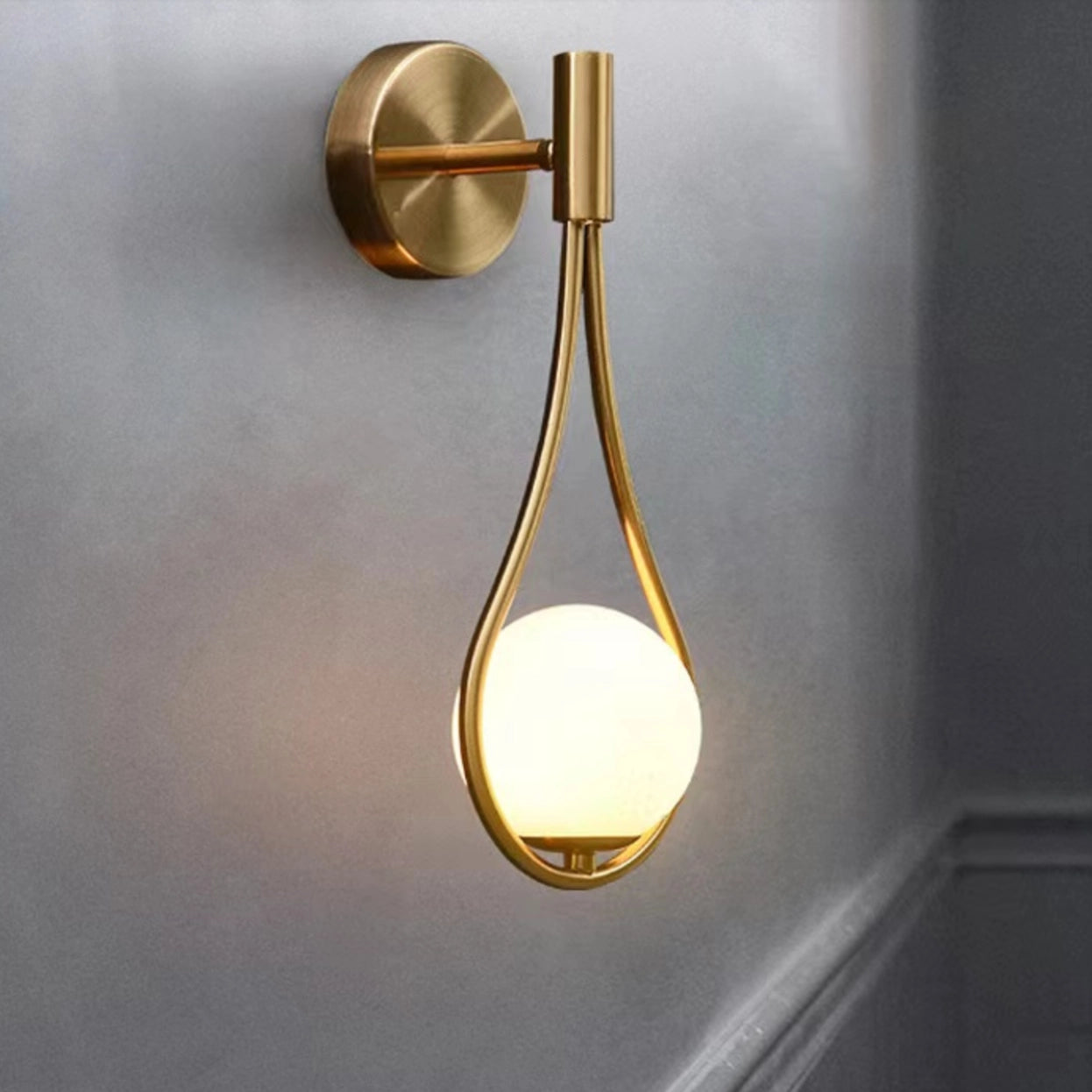 Gold brass wall sconce featuring a modern geometric globe lamp design, luxury lighting fixture with a circular shape.