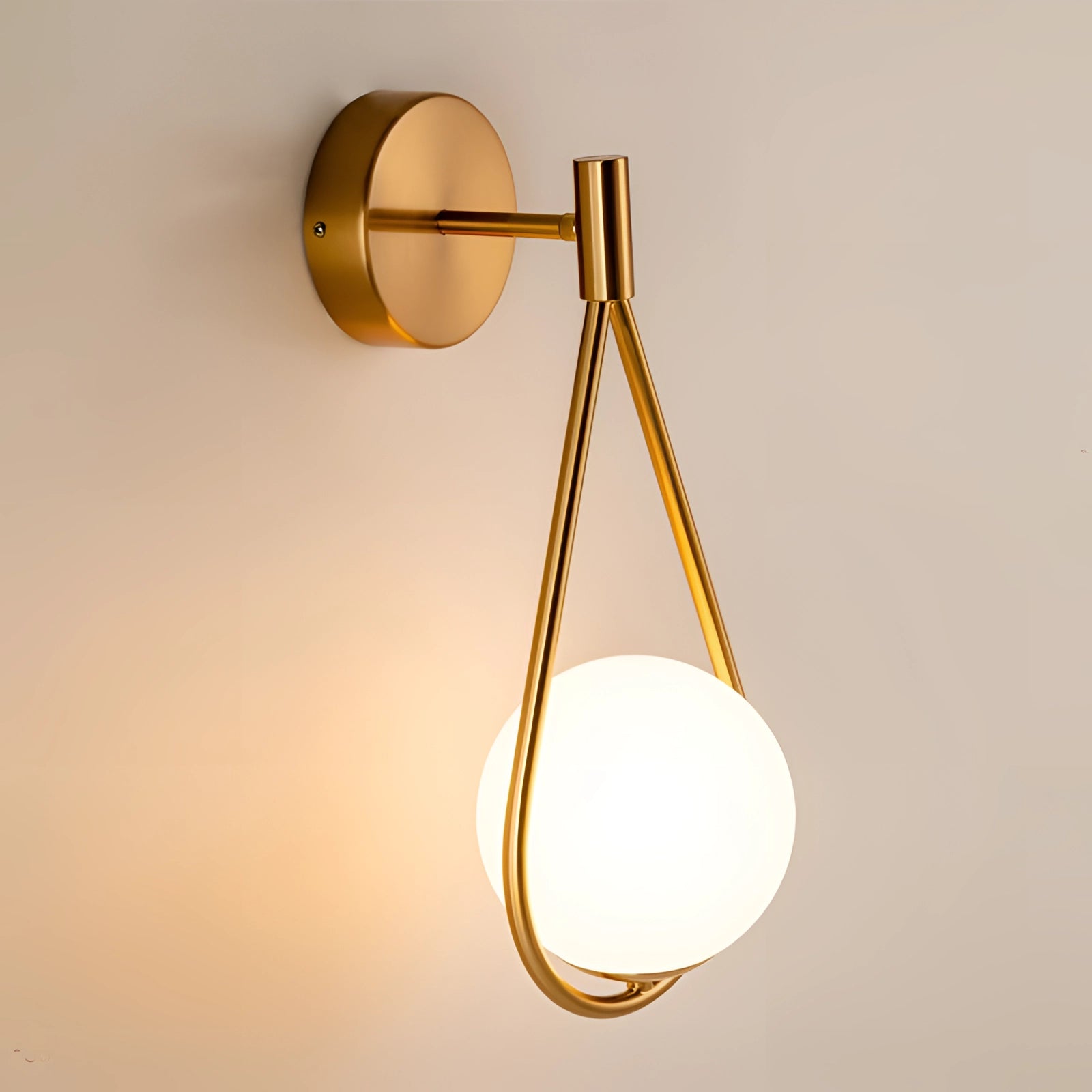 Modern geometric globe lamp made of gold brass, mounted on a wall, featuring an amber-tinted lampshade, luxury lighting.