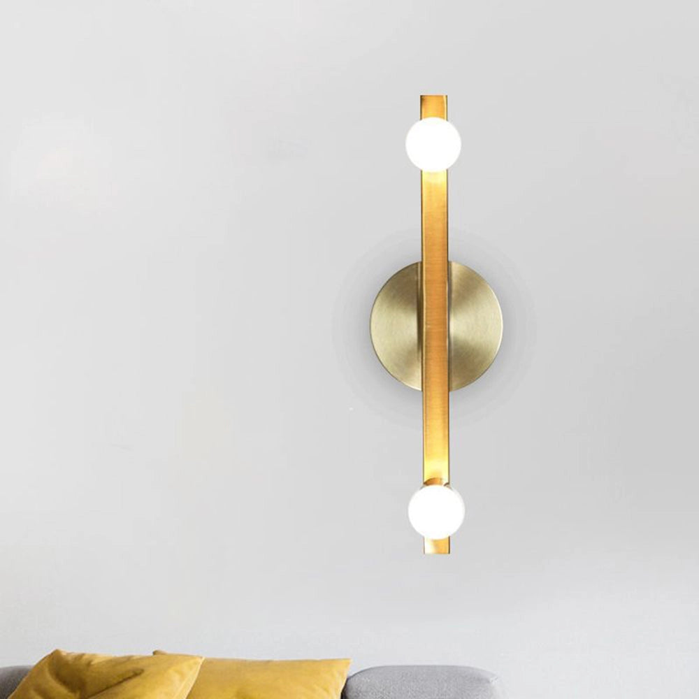 Gold dual globe wall sconce with a modern brass finish mounted on a wall, featuring two spherical glass shades and minimalist design elements.