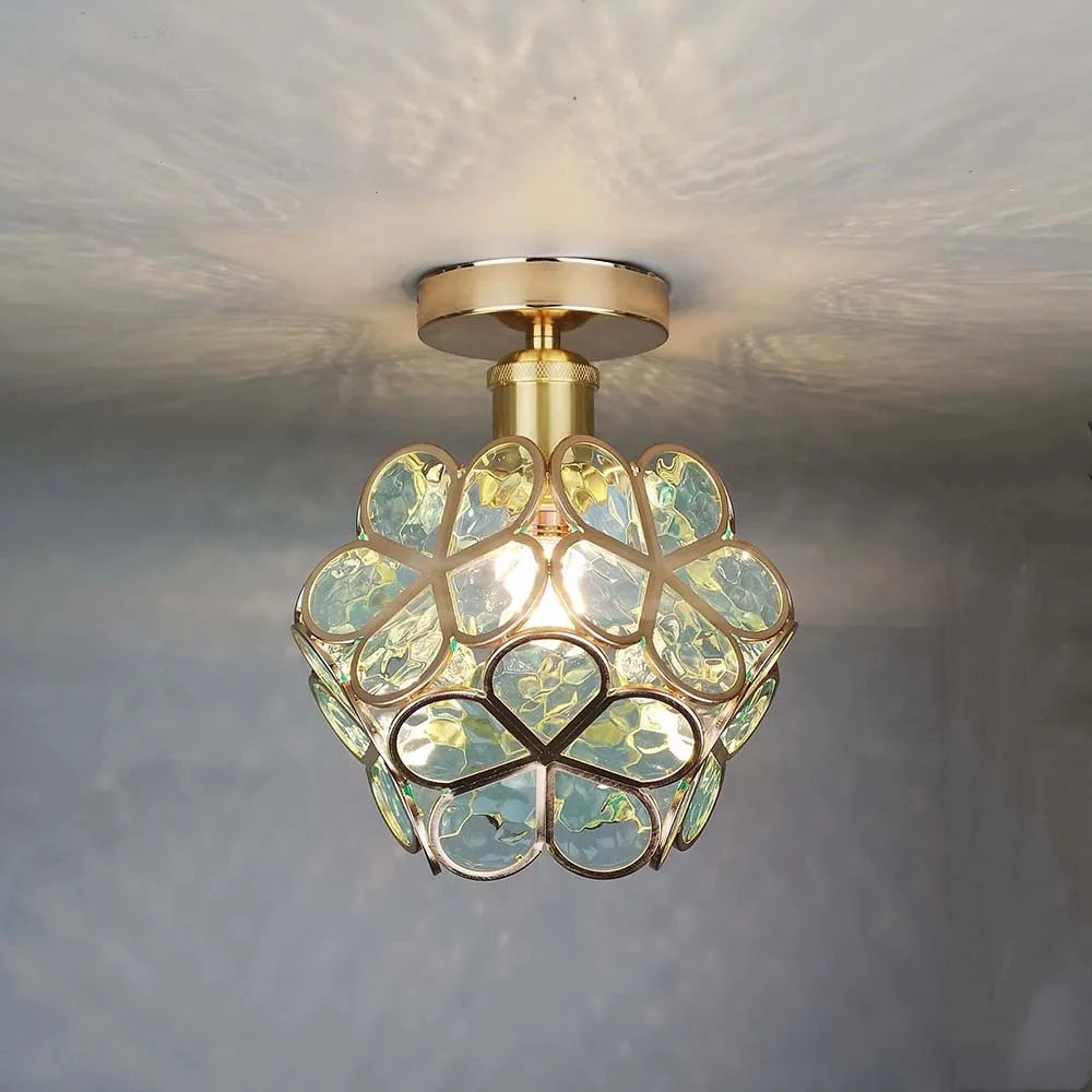 Gold flush mount ceiling light with a modern geometric design, featuring an artistic glass lampshade in amber tones, showcasing symmetry and contemporary style.