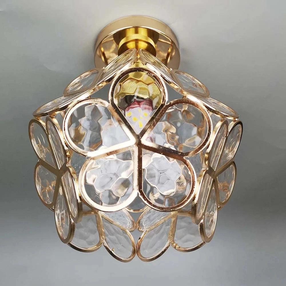 Modern geometric ceiling light with artistic gold flush mount design, featuring a clear glass shade.