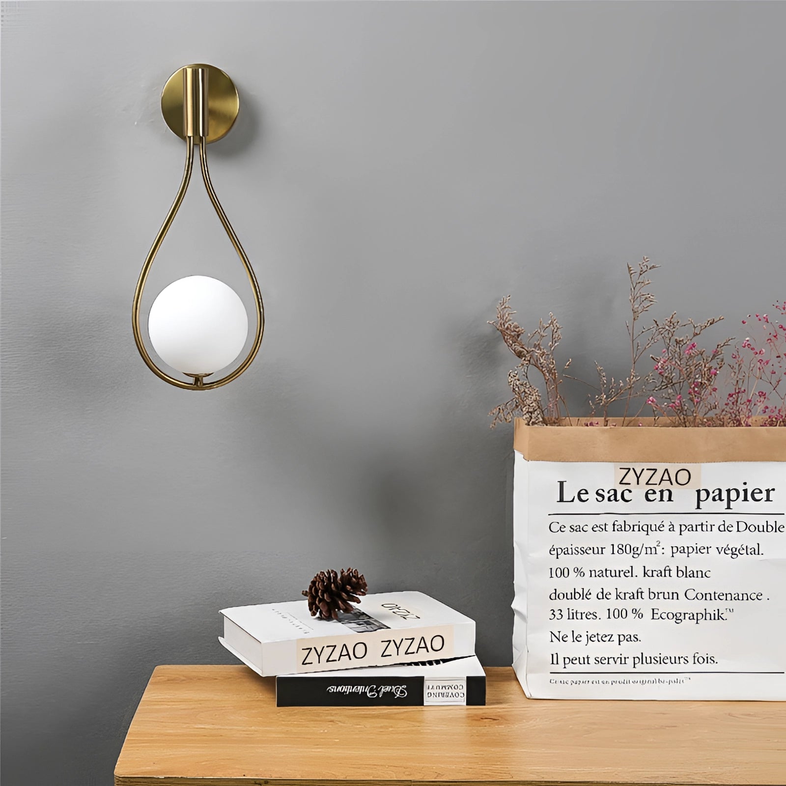 Gold globe wall sconce mounted on a wood-paneled wall, featuring a modern brass design with its warm yellow light illuminating the room.
