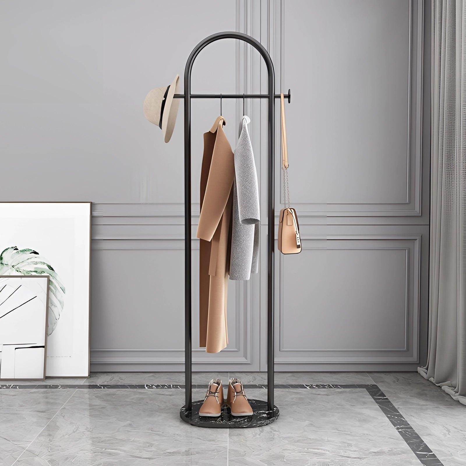 Gold metal coat rack with a marble base in black, featuring a minimalist and luxurious design, standing in a room with a sleek appearance.