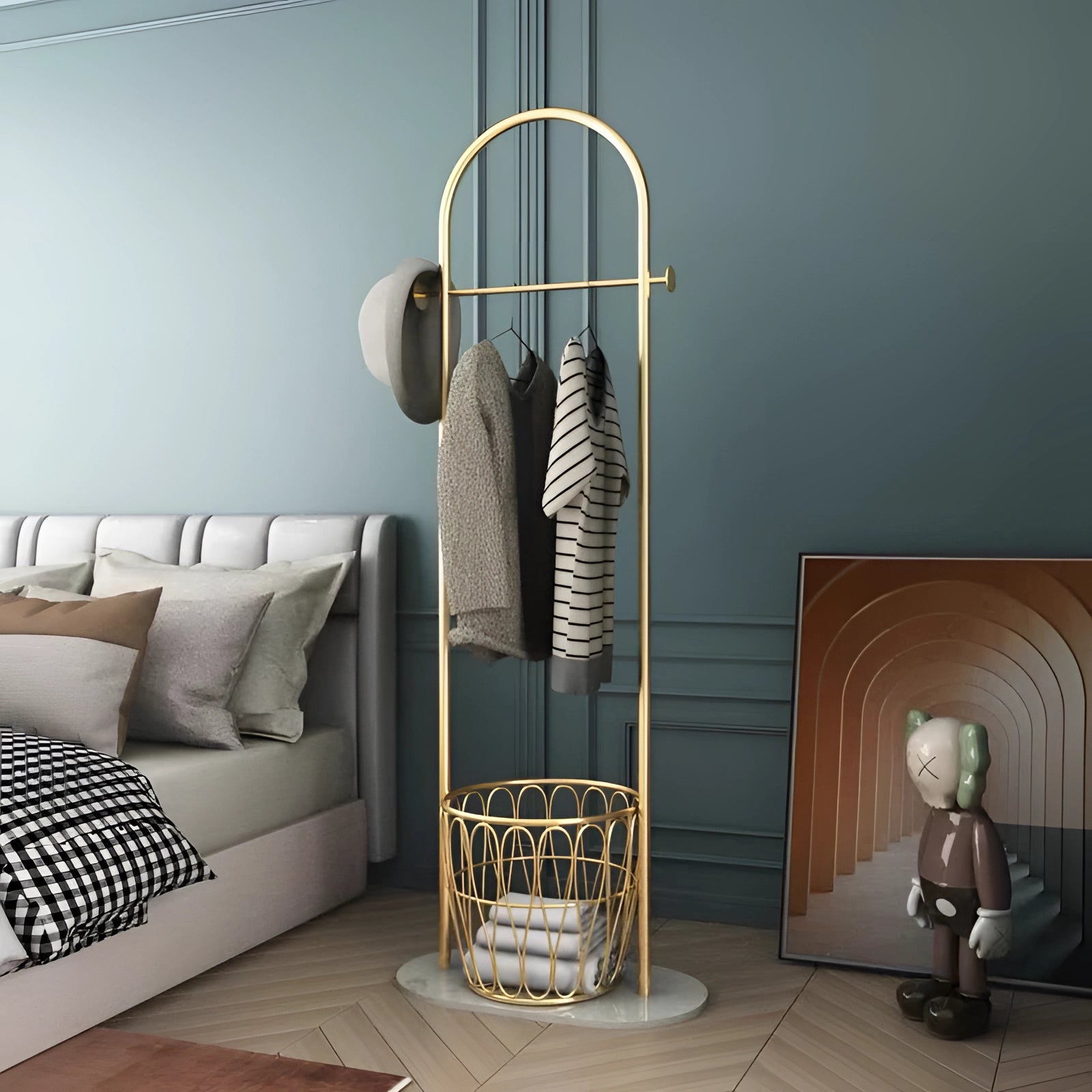 Gold metal coat rack with marble base in a minimalist luxury design, placed on a grey flooring surface, emphasizing a sleek and elegant interior aesthetic.