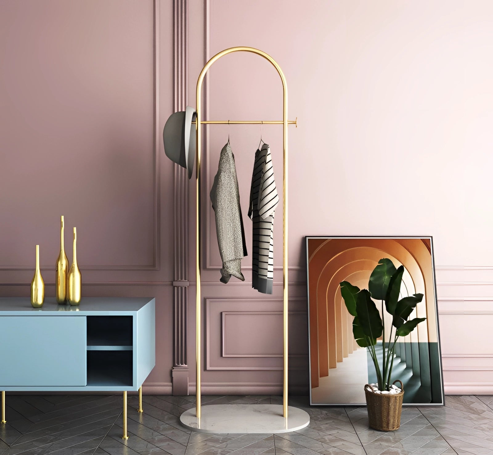
A gold metal coat rack with a marble base displayed in a minimalist, luxurious interior setting, featuring houseplants and elegant furniture.