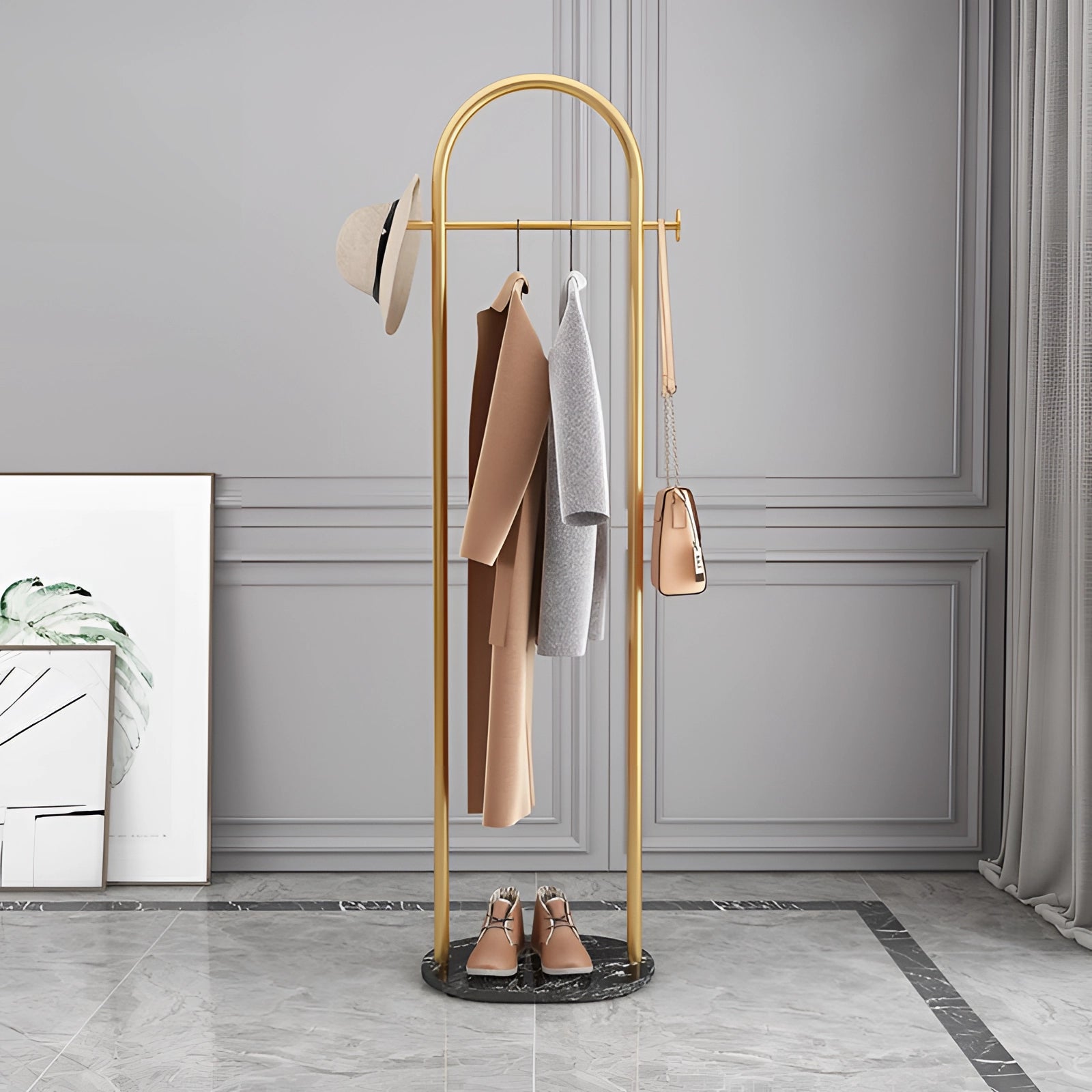 Gold metal coat rack with a marble base, featuring a minimalist and luxurious design. The base is black and made of marble, providing a sturdy foundation. The coat rack is set against a simple indoor environment, emphasizing its elegant and modern aesthetic.