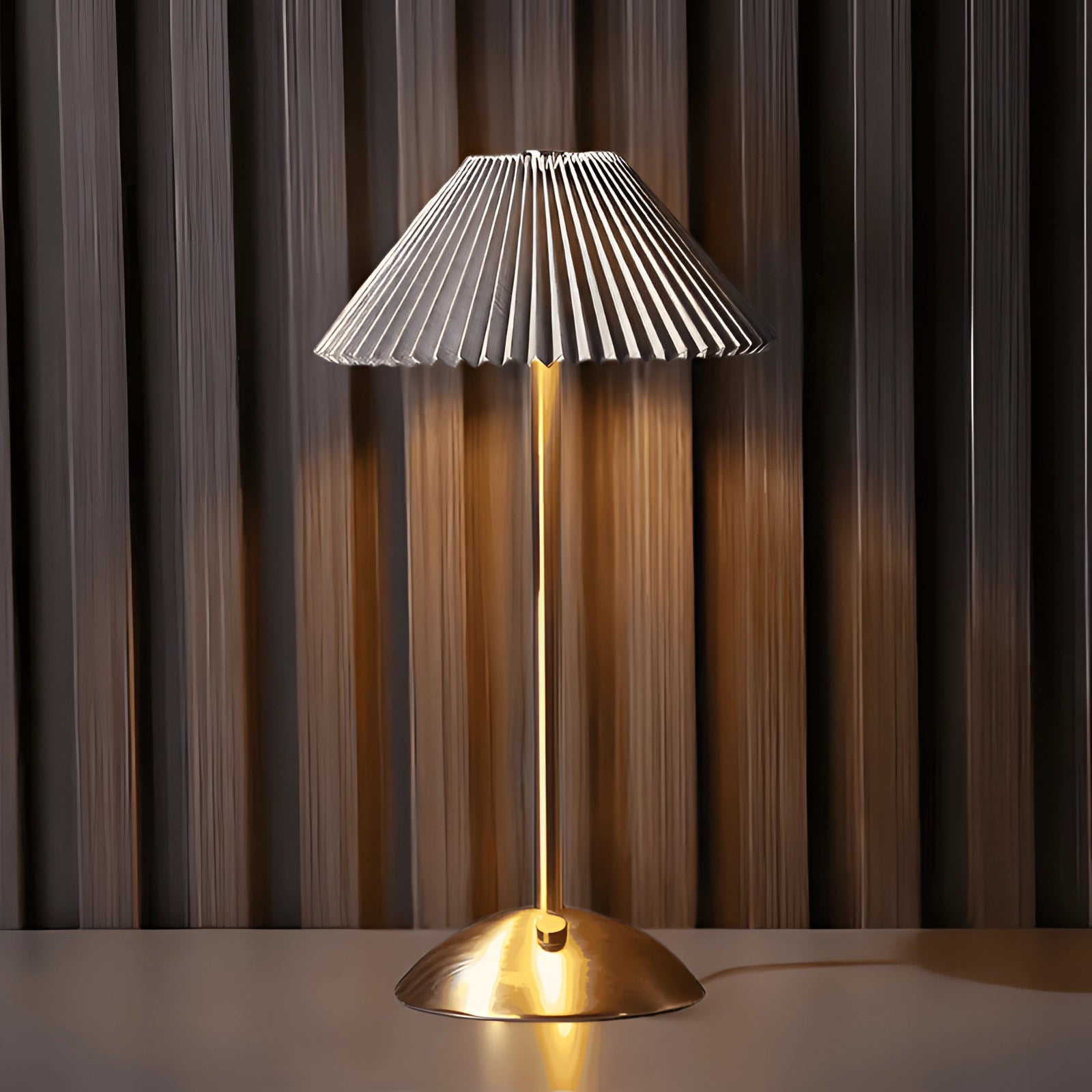 Gold mid-century brass floor lamp with pleated lampshade, featuring a sleek design and Braun finish, standing on a wooden floor.