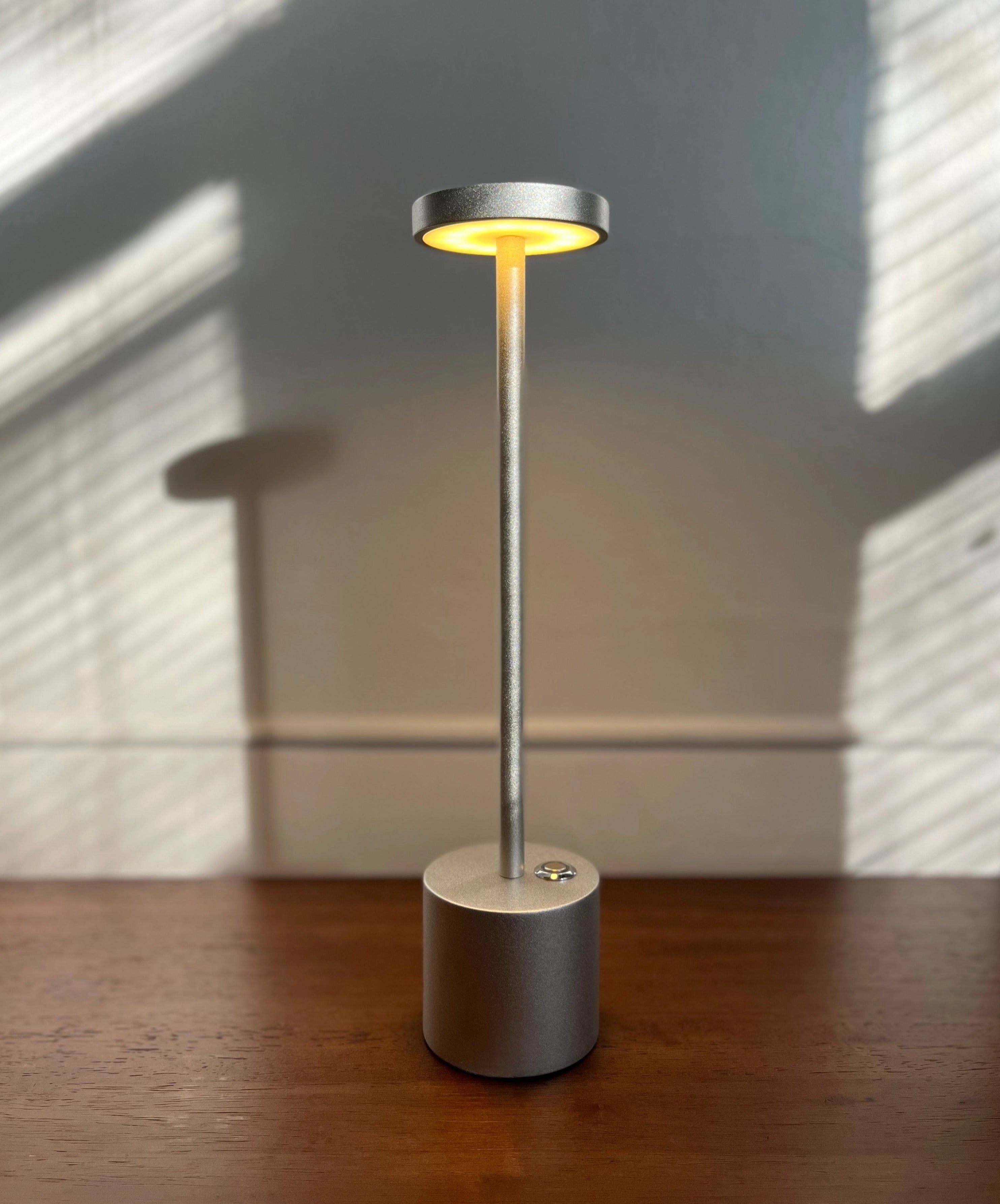Gold minimalistic LED desk lamp with a circular head, brass finish, and stylish design, placed on a wooden desk.