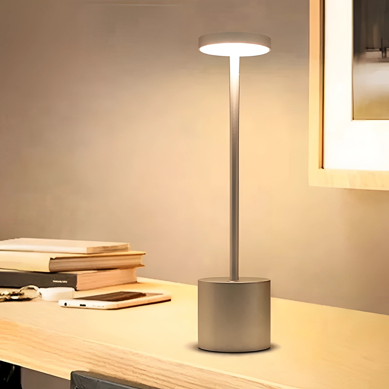 Gold minimalistic LED desk lamp with a circular head and brass finish, placed on a wooden table, enhancing the stylish interior design.