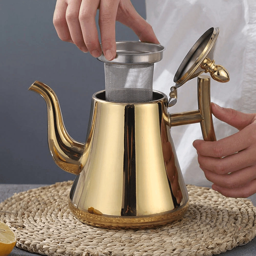 Gold stainless steel luxury teapot with a modern elegant design, showcasing a glossy finish, perfect for serving tea or other hot beverages in a sophisticated kitchen setting. The teapot is situated on a countertop, embodying a blend of functionality and stylish serveware.