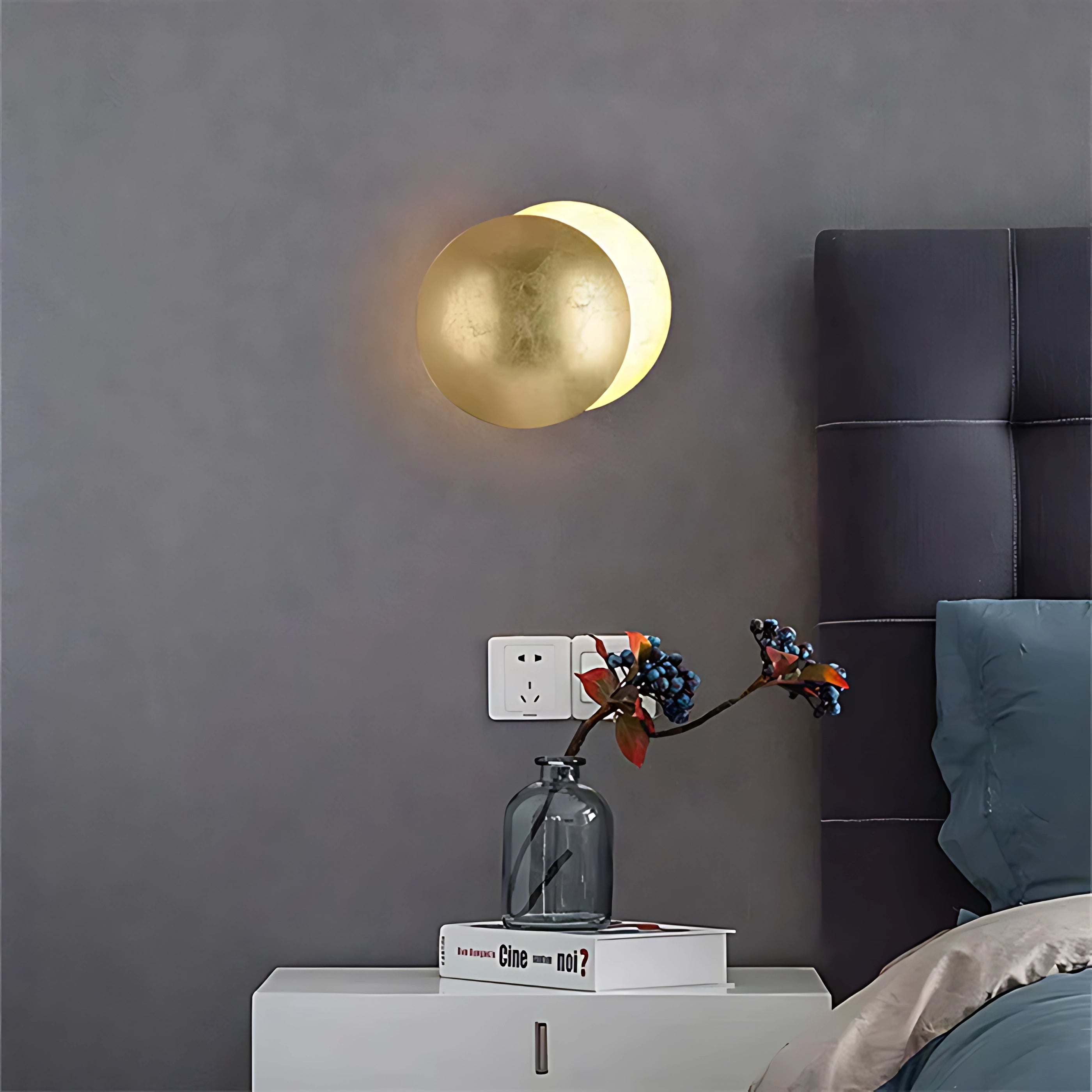 Golden LED wall lamp with a modern circular design in a brass-like yellow finish, providing ambient lighting to a room. The fixture is mounted on a wall, showcasing its metallic sheen and contemporary aesthetic.