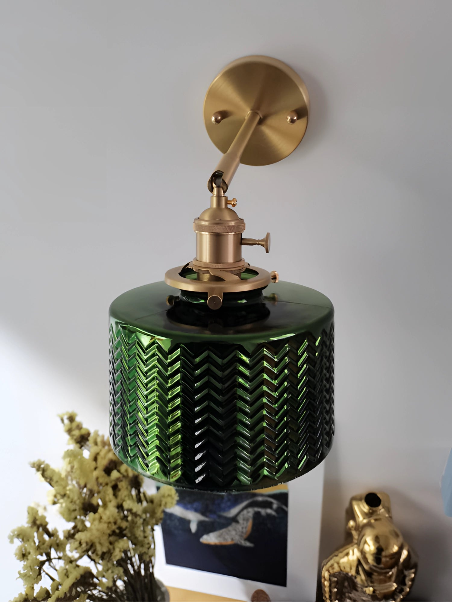 Green chevron wall lamp with a brass finish, featuring a geometric pattern, mounted on a wall.