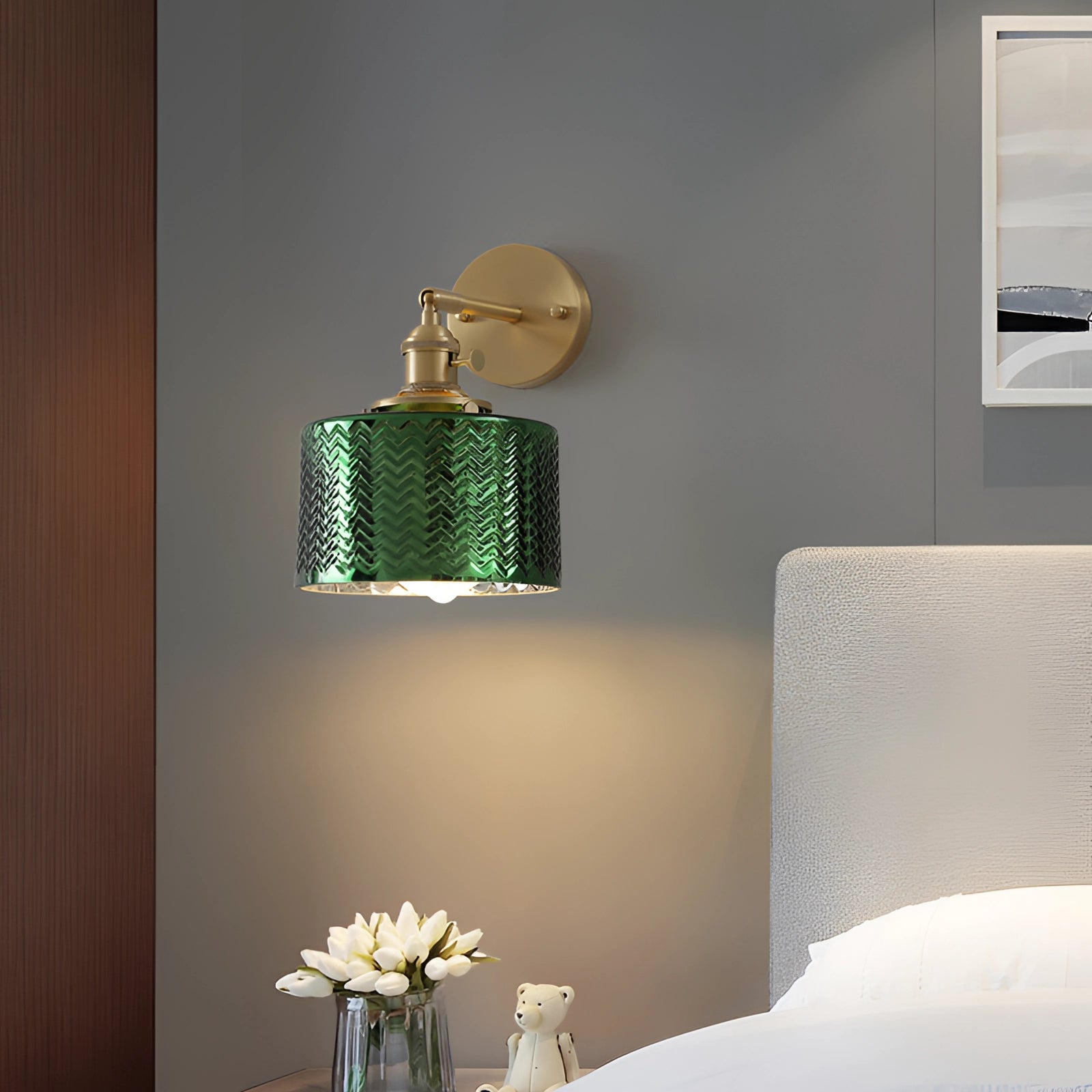 Green chevron wall lamp with a brass sconce and geometric pattern, mounted on a wall, with a rectangular shade, surrounded by elements of interior design including a plant and wooden accents.