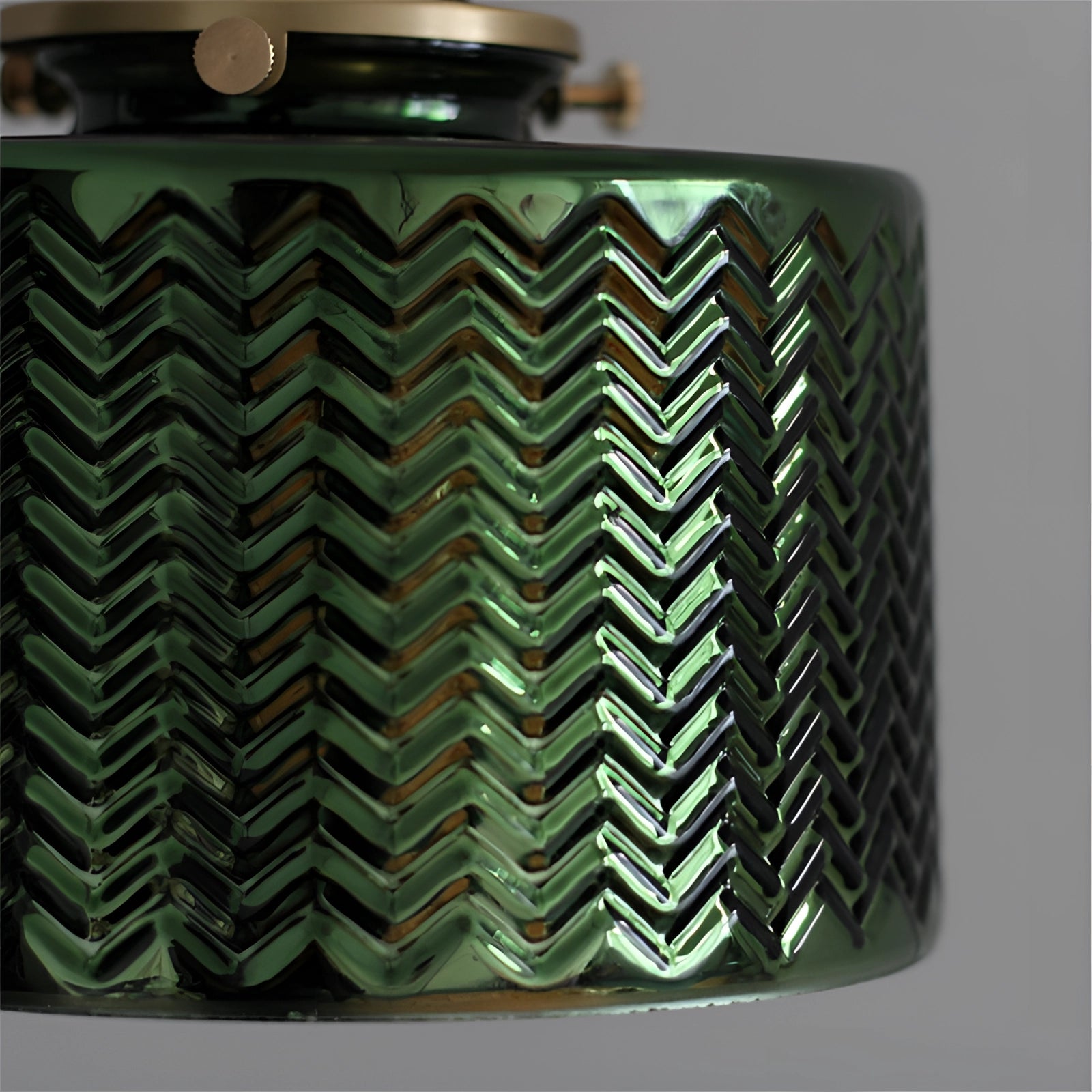 Green chevron wall lamp featuring a brass sconce with a geometric pattern design.