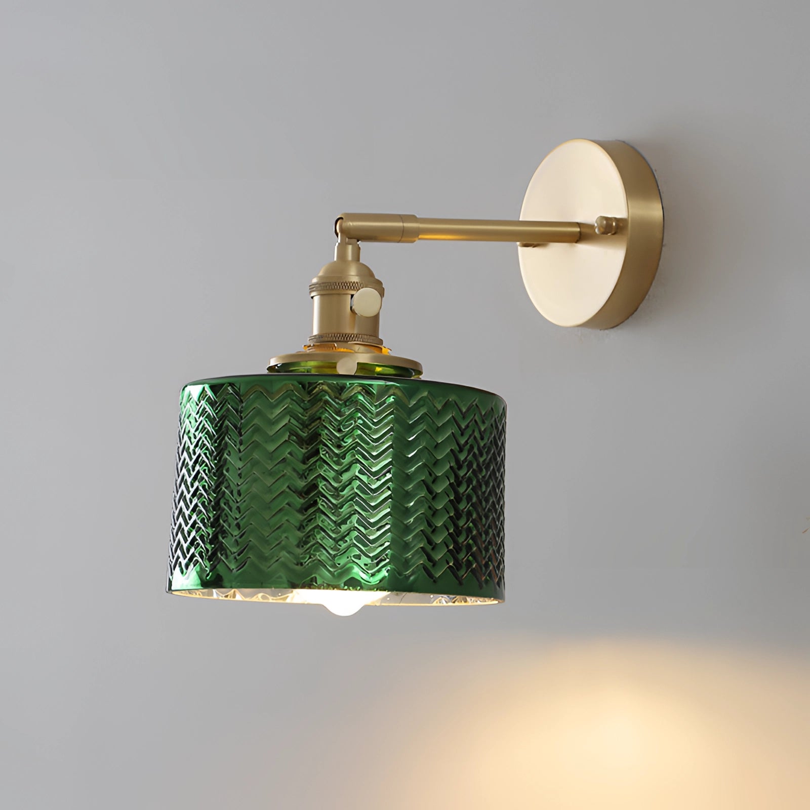 A green chevron wall lamp with a geometric pattern, featuring a brass sconce design.