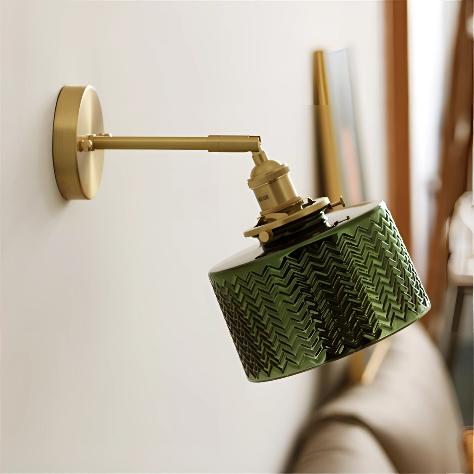 Green chevron wall lamp with a brass sconce featuring a geometric pattern, mounted on a wall.