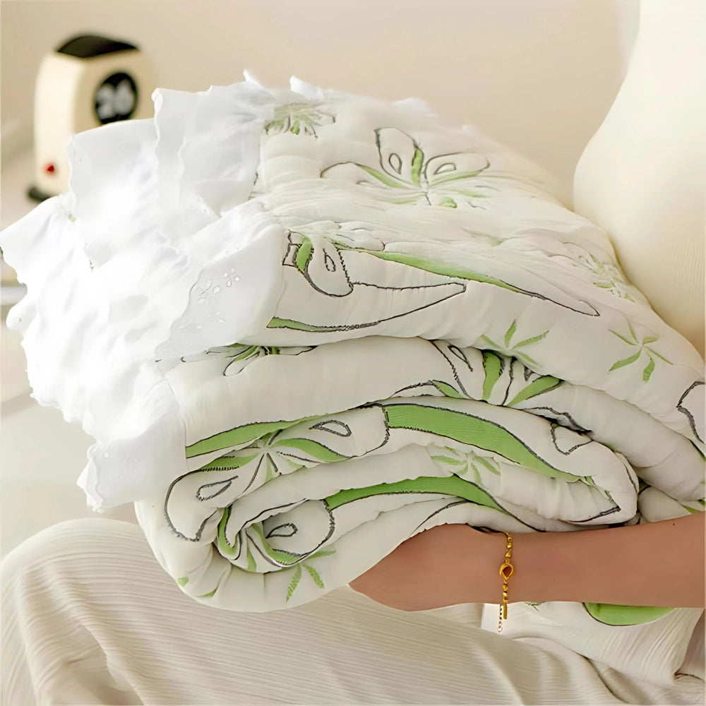 Green floral luxury bedding set featuring a designer duvet cover with intricate patterns, placed on a neatly made bed. The fabric appears soft and comfortable, surrounded by matching linens, creating an elegant and inviting bedroom ambiance.
