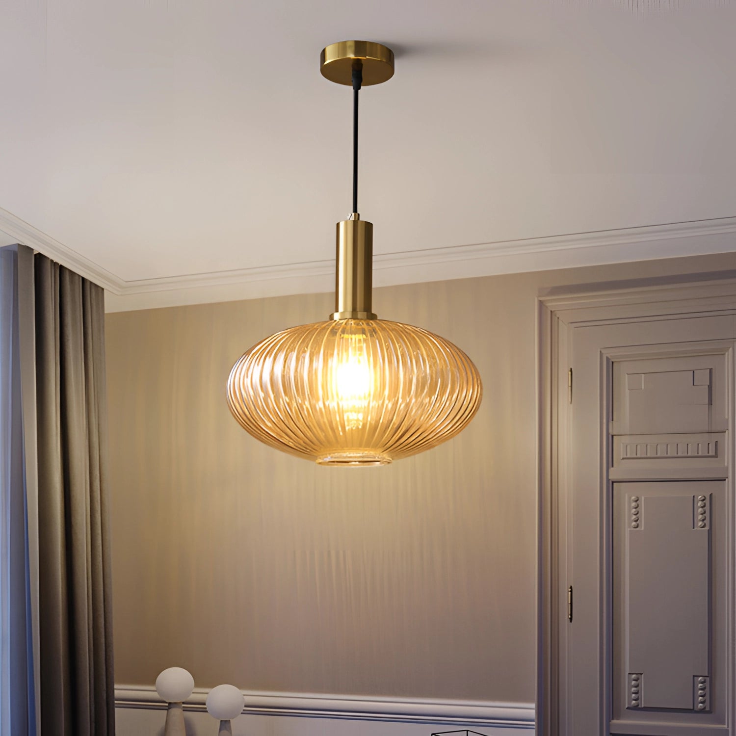 Modern Scandinavian interior featuring a Green Ribbed Glass Pendant Light with Gold Accent hanging from the ceiling, illuminating the space with warm amber tones, complemented by wooden elements and a stylish curtain in the background.