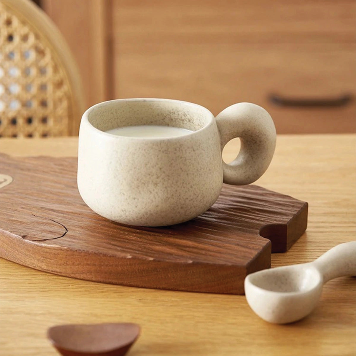 Handcrafted speckled ceramic mug with a brown finish, placed on a wooden table, showcasing its eco-friendly artisan design.