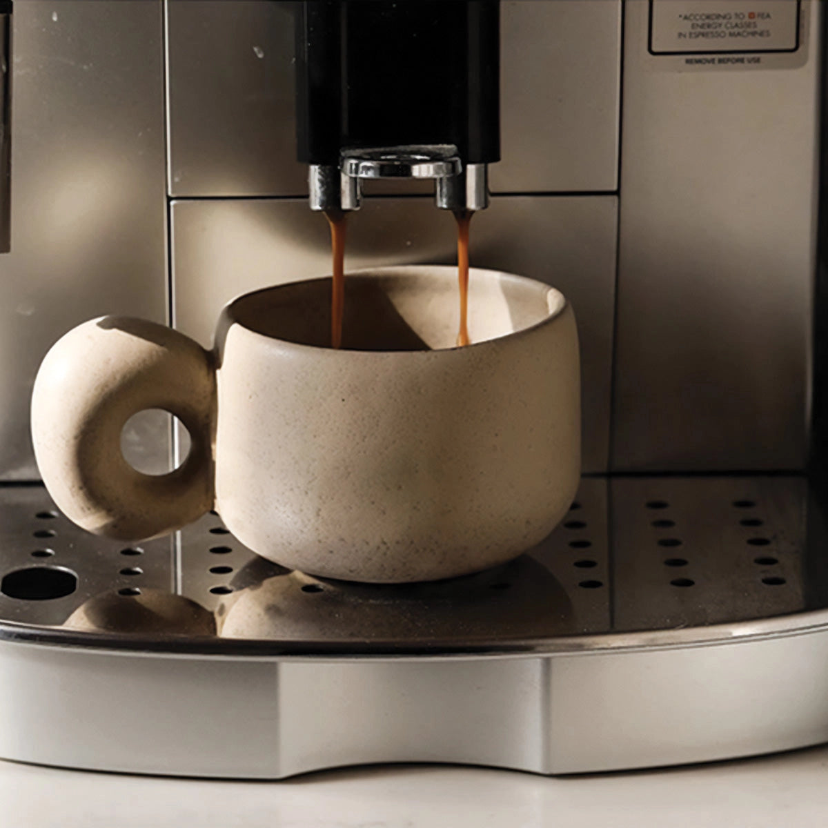 Handcrafted speckled ceramic mug featuring an eco-friendly artisan design, perfect as a coffee cup, displayed on a shelf.