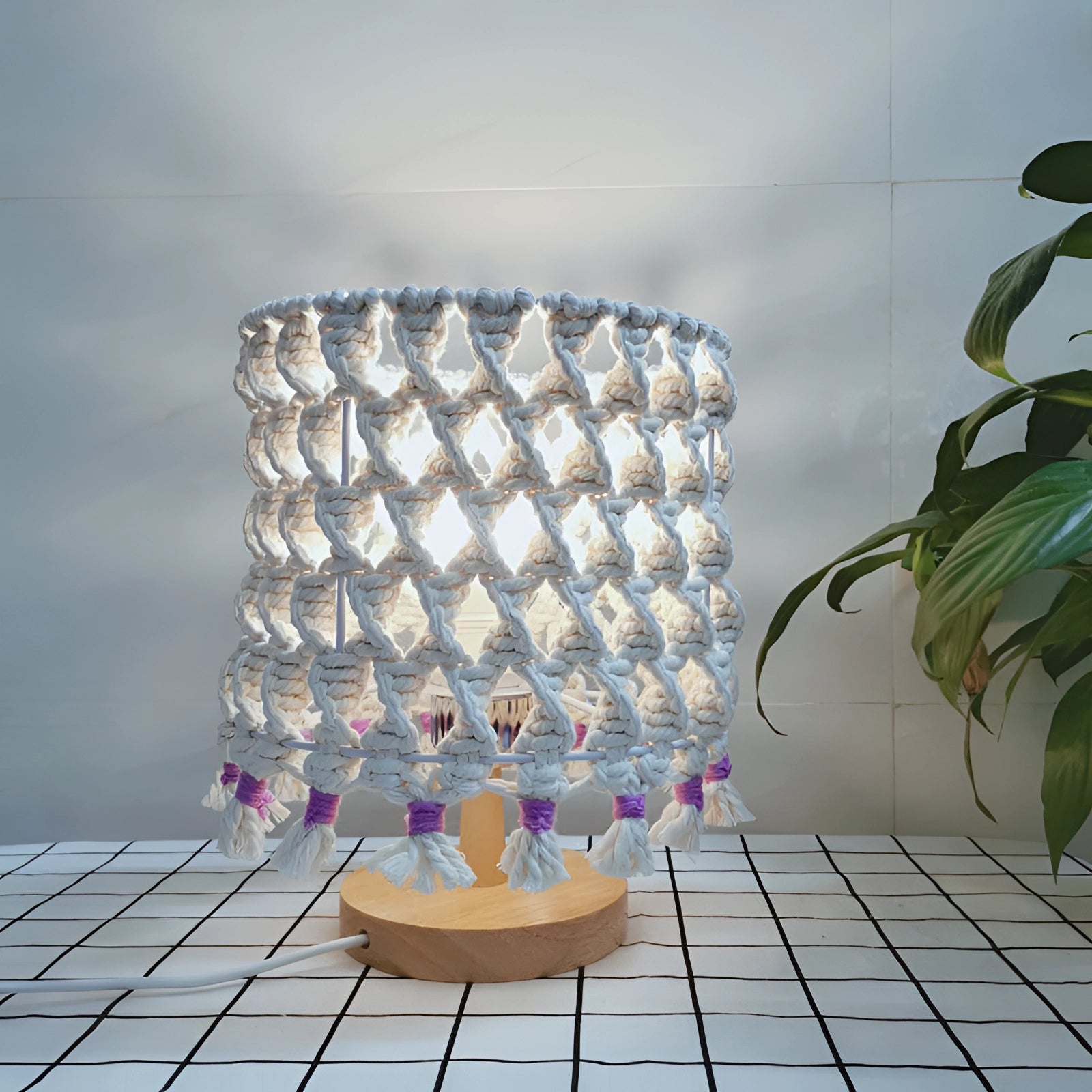 Handmade Boho Macrame Lampshade with unique tassel design hanging in a cozy interior setting, surrounded by a houseplant in a flowerpot and a chair.
