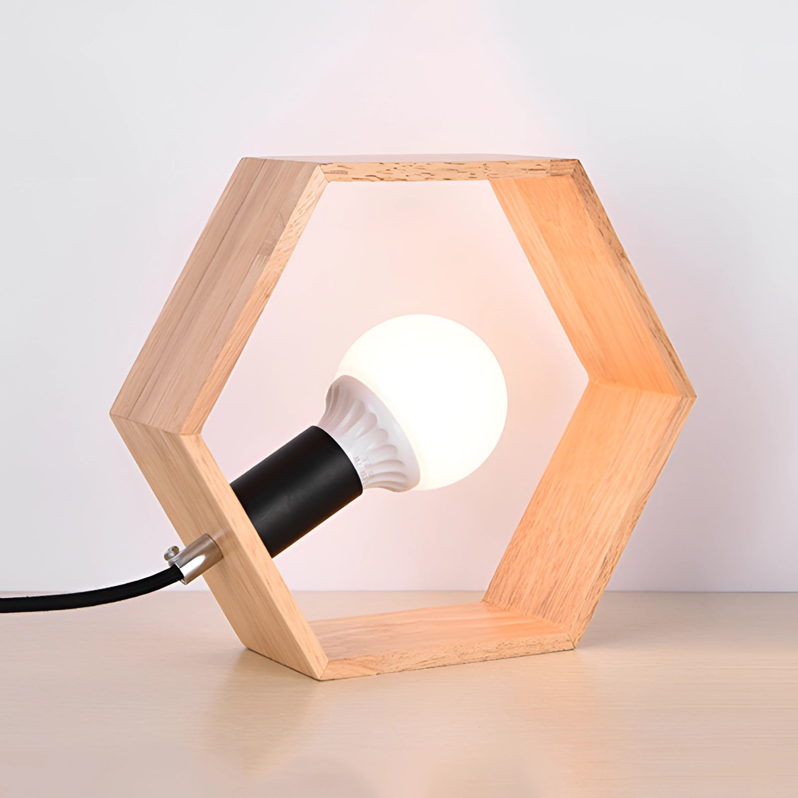 Hexagonal wooden lamp with a minimalist geometric design, featuring a warm hardwood finish and soft lighting, suitable for desk placement.