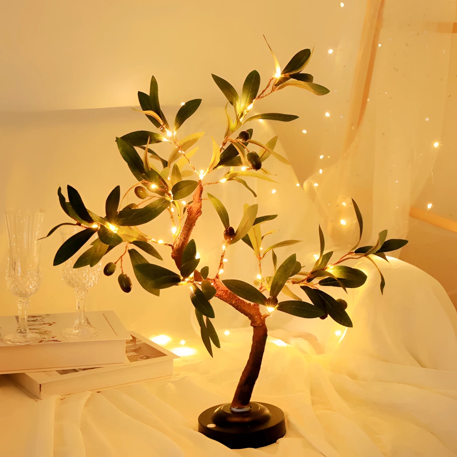 Decorative olive tree lamp with LED lights, featuring realistic green leaves and branches, housed in a stylish flowerpot, designed for indoor use. Placed near a window, it enhances interior design with its natural and elegant appearance.