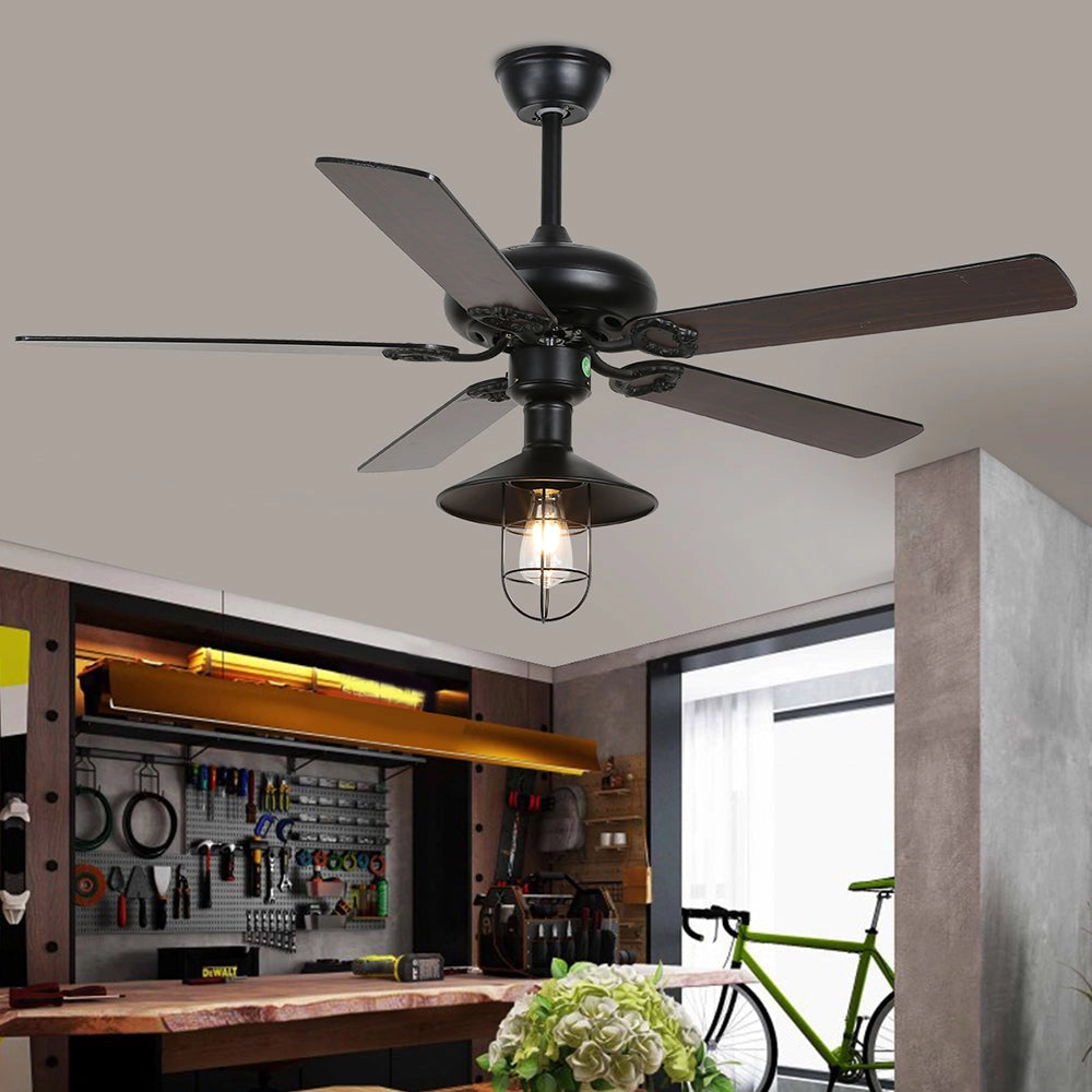Industrial black ceiling fan with light and remote, featuring a rustic vintage design, mounted on a wooden ceiling in a stylish interior setting.