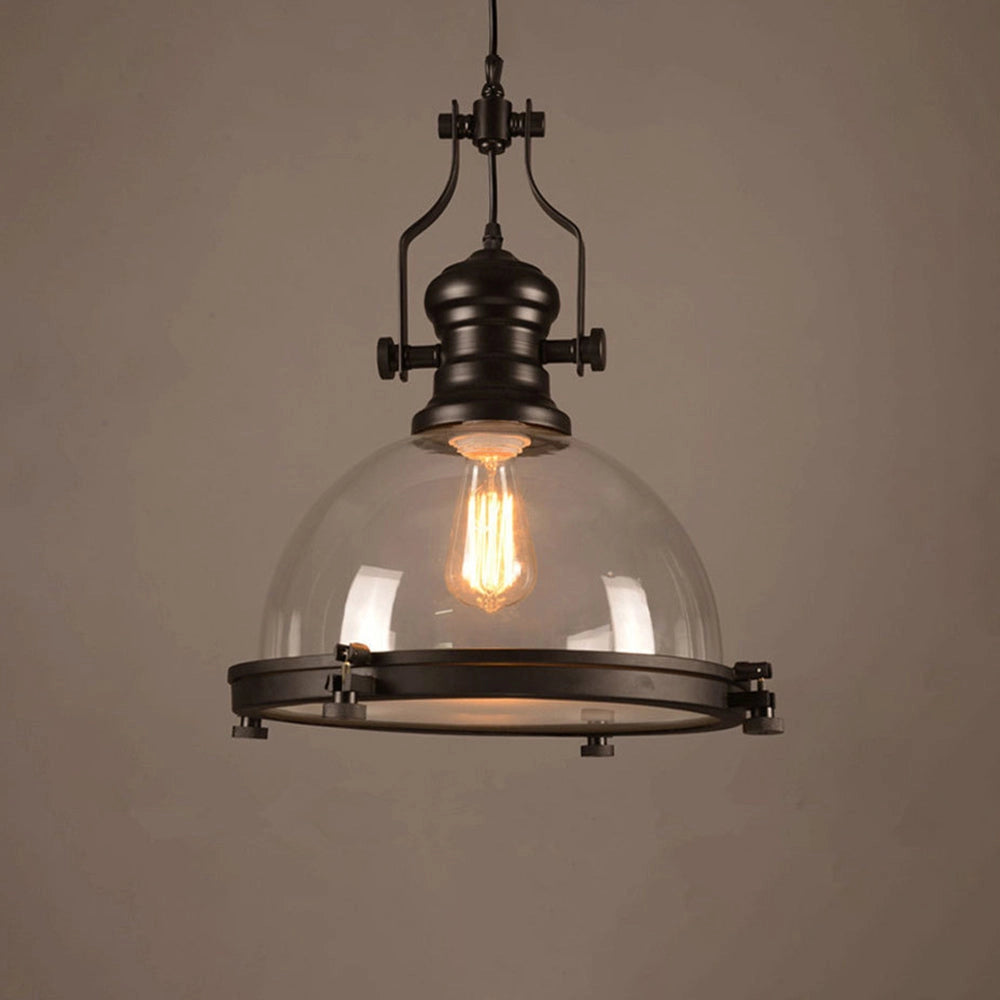 Industrial black iron pendant light with a retro adjustable design featuring a frosted glass dome, hanging from a ceiling fixture. The light emits a warm amber glow, providing a vintage aesthetic suitable for various interior styles.