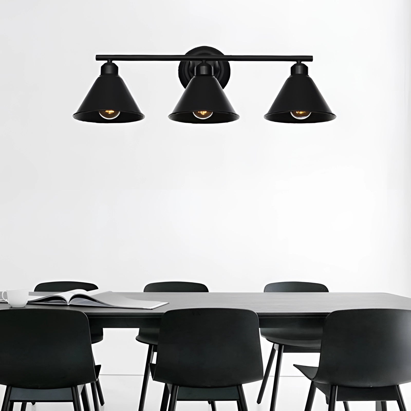 Industrial geometric metal cage pendant light with an Edison bulb fixture hanging above a table and chair, showcasing a modern black and white design.