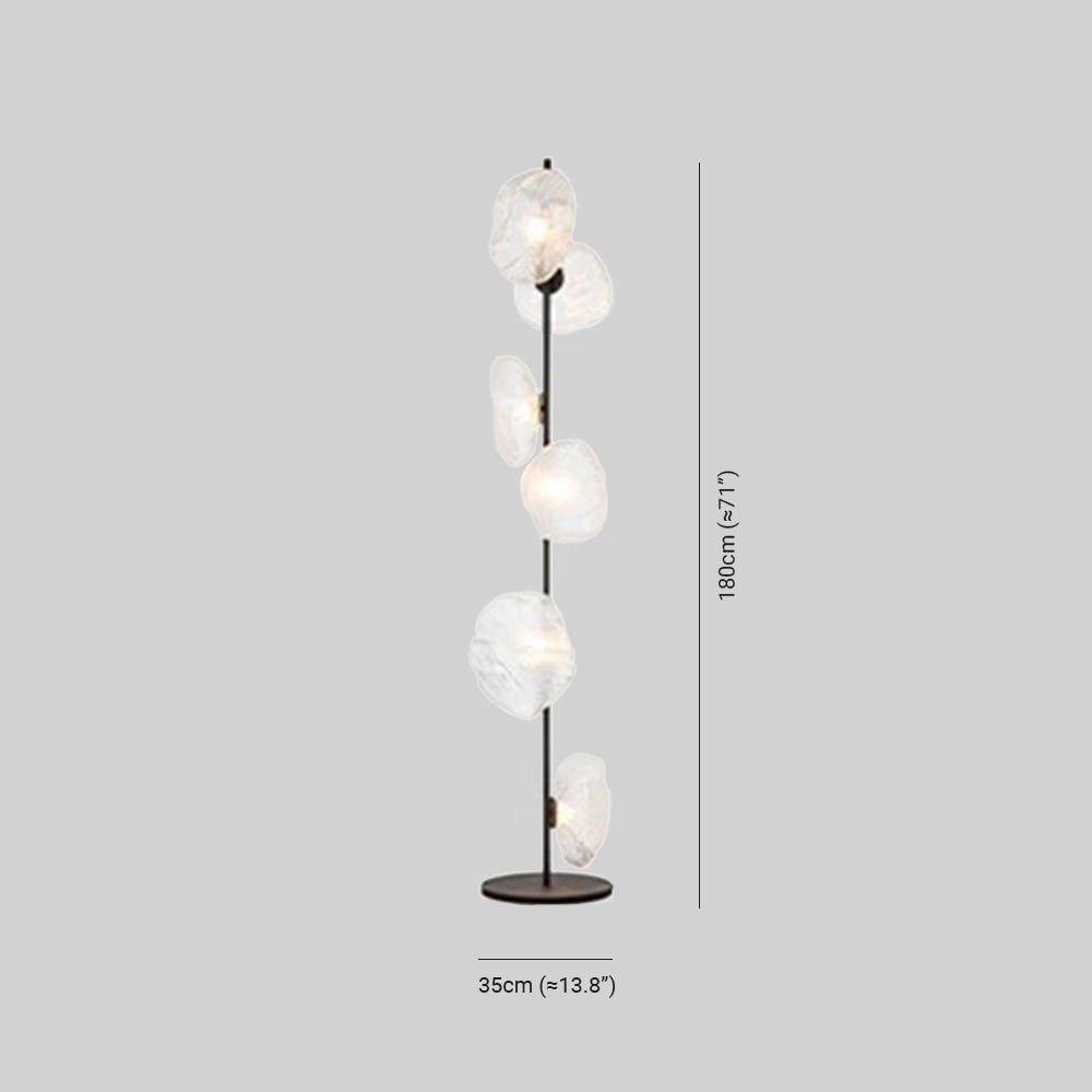 Industrial metallic pebble floor lamp with a sculptural design, featuring a circular metal base and a transparent lampshade.