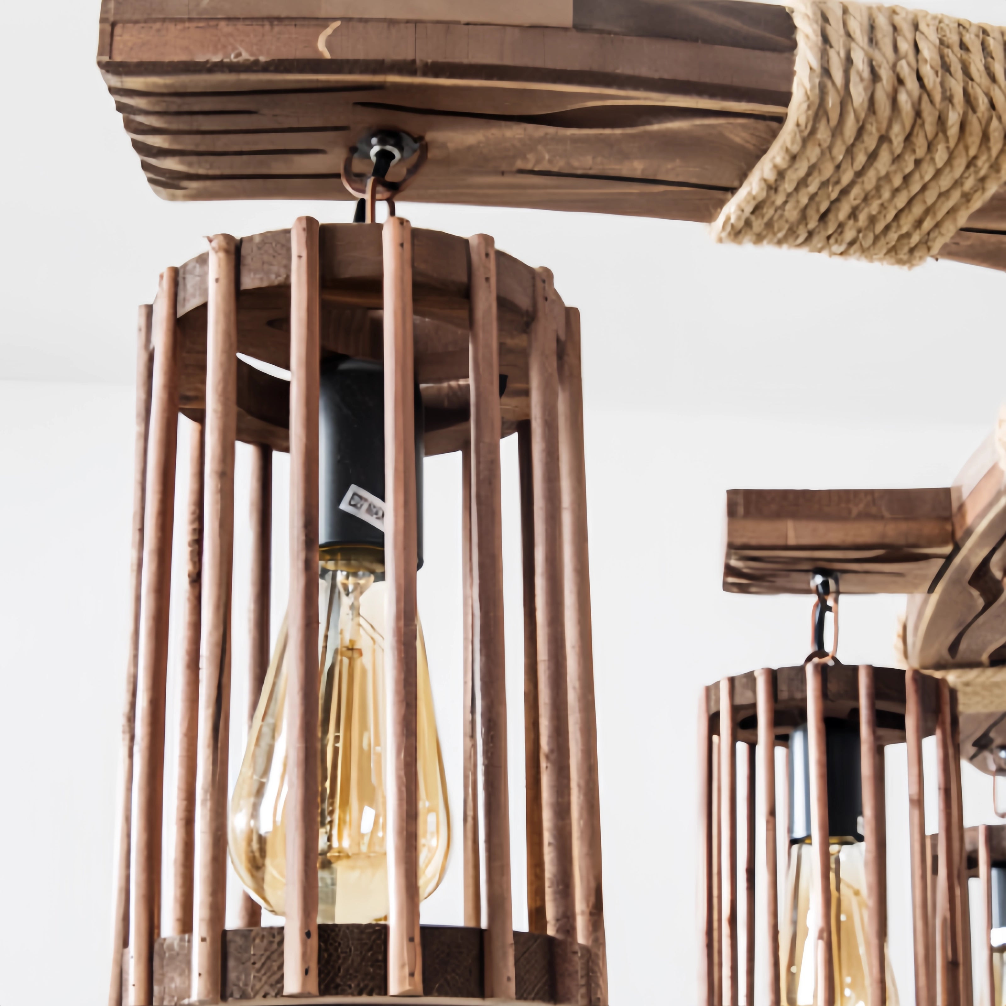 Industrial vintage cage pendant light with a rustic wood beam chandelier design, featuring a combination of wood and metal elements. The pendant light includes intricately designed cage shades and is mounted to the ceiling, highlighting the stained hardwood finish.