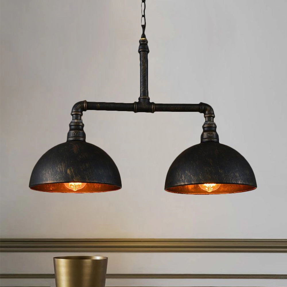 Industrial-style black metal pendant light with dual dome-shaped shades, hanging from a ceiling. The design includes exposed piping and is reminiscent of vintage fixtures, suitable for adding a rustic charm to interiors.