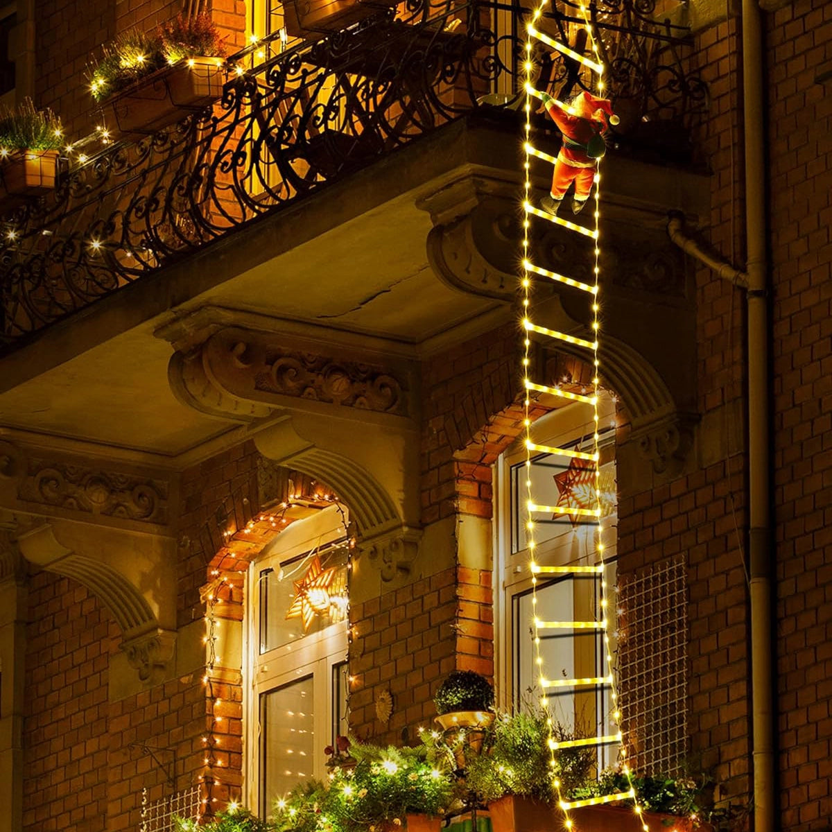 LED Climbing Santa with Festive Garland displayed in a warmly lit interior setting, featuring a cozy holiday decor theme with ambient yellow lighting and a view of a city building through a window.