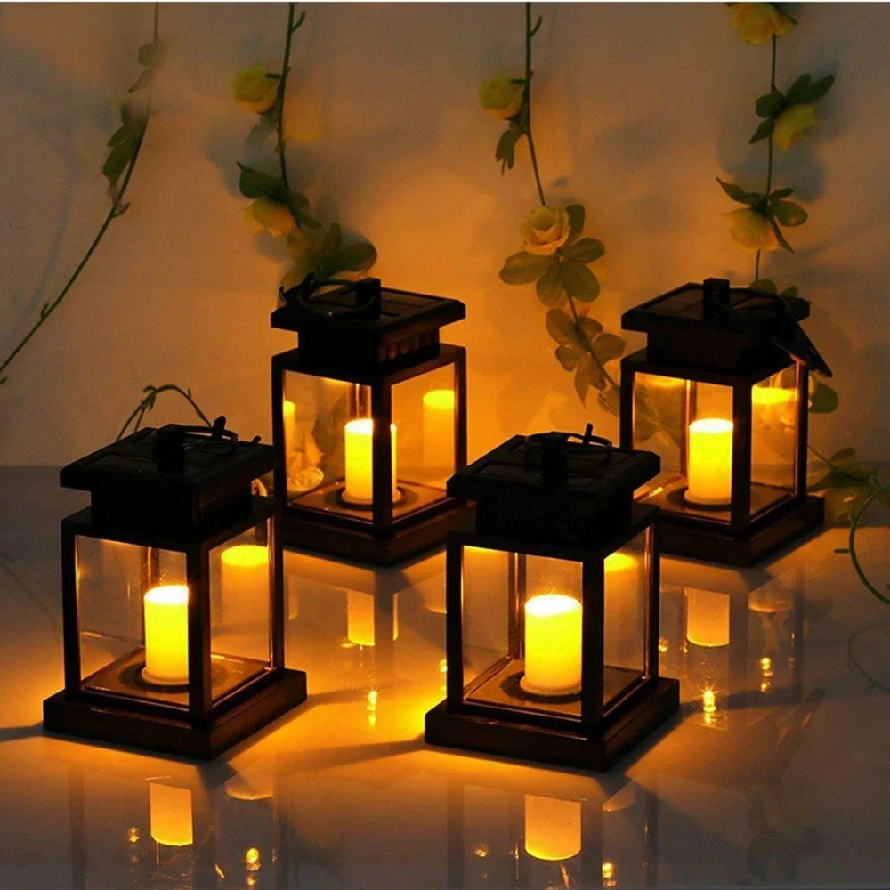 A black metal LED decorative outdoor lantern with a flameless design, featuring a rectangular shape and waterproof construction, set against a natural backdrop with branches and wood elements.