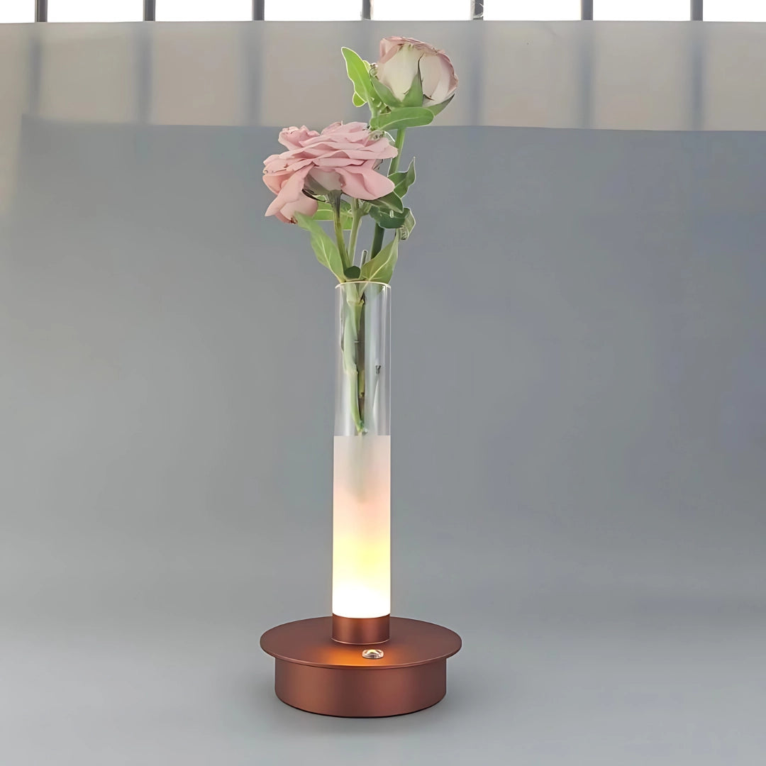 Modern frosted glass vase with LED illumination in a minimalist design, featuring a Braun color variant. The vase includes artificial flowers with delicate petals, adding a decorative touch.