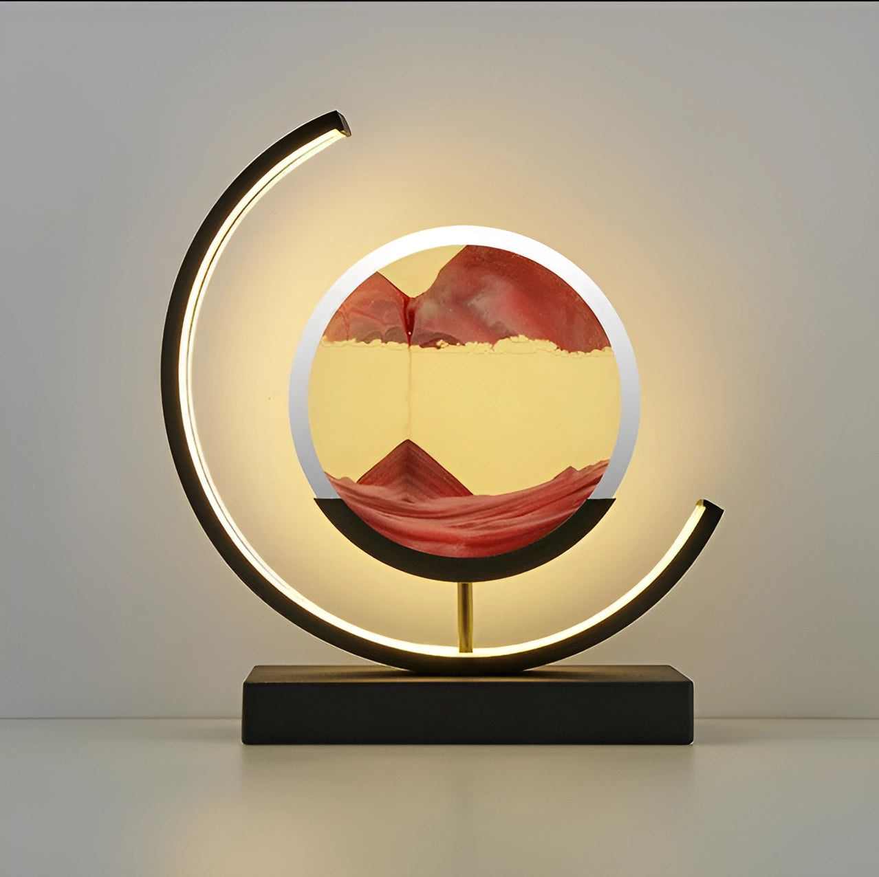 
A crescent moon-shaped LED lamp with red kinetic sand, designed to provide mood lighting. The lamp features artistic elements with an amber glow, set within a metal oval frame.
