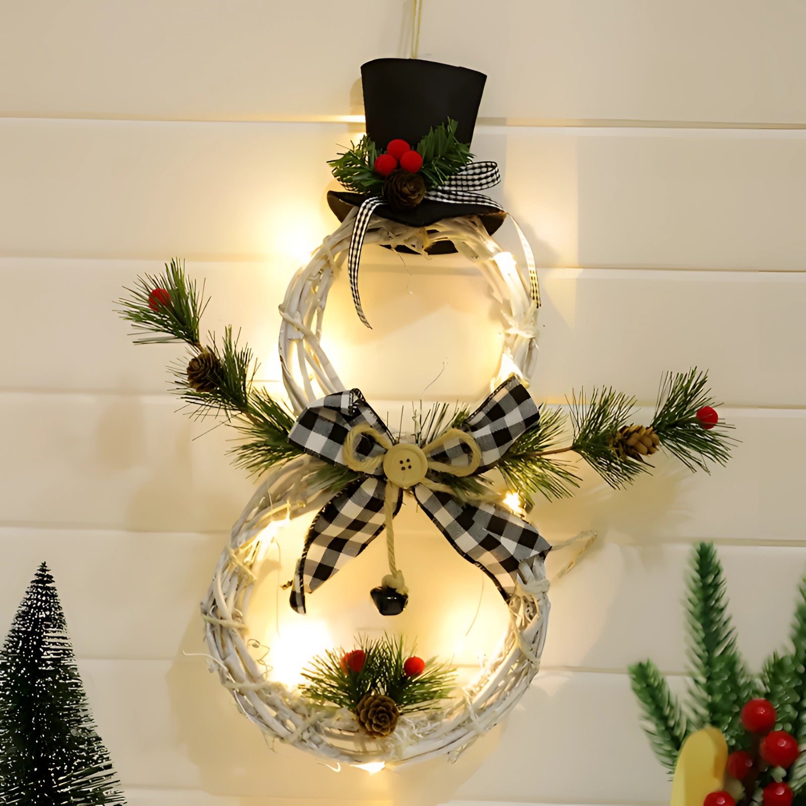LED snowman wreath featuring rustic black accents, adorned with evergreen branches and holiday ornaments, illuminated by lights for a charming Christmas decoration.