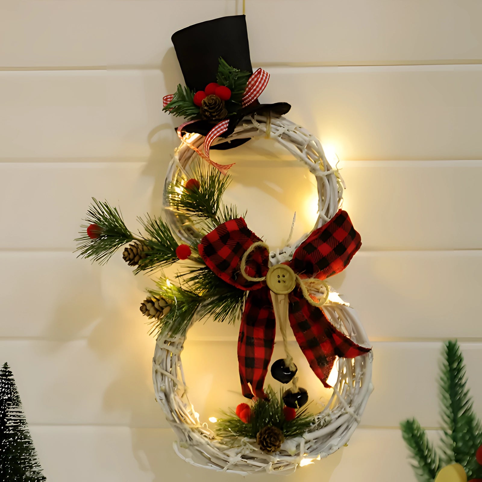 LED snowman wreath featuring a rustic design with a battery-operated light, accented by a red hat and holiday decorations, including twigs and evergreen foliage, perfect for Christmas decor.