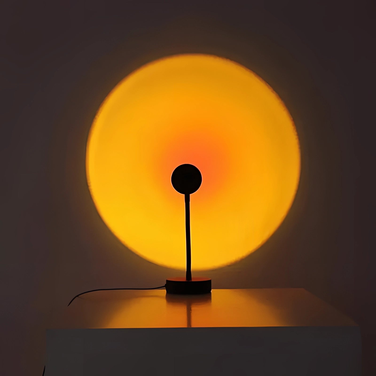 
A USB-powered LED sunset projection lamp with a stand, emitting a warm amber and orange glow, resembling a sunset with circular patterns.