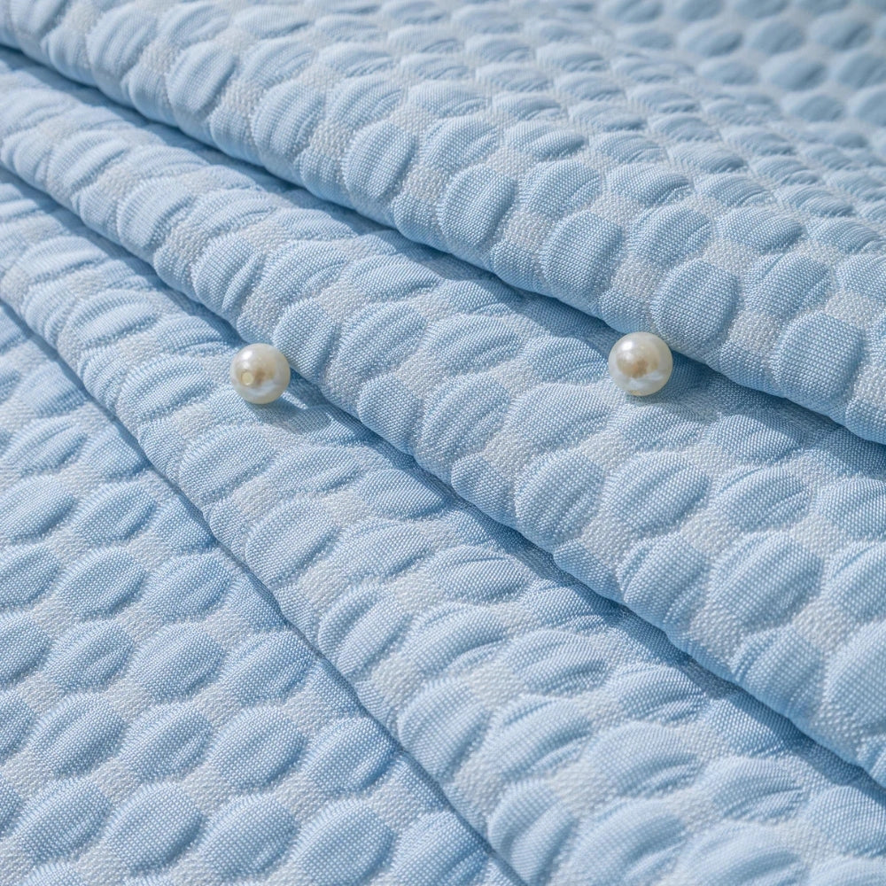 Light blue quilted sofa cover with a textured pattern, designed to be anti-slip and pet-friendly, shown in a close-up view highlighting its durable textile and aqua color.