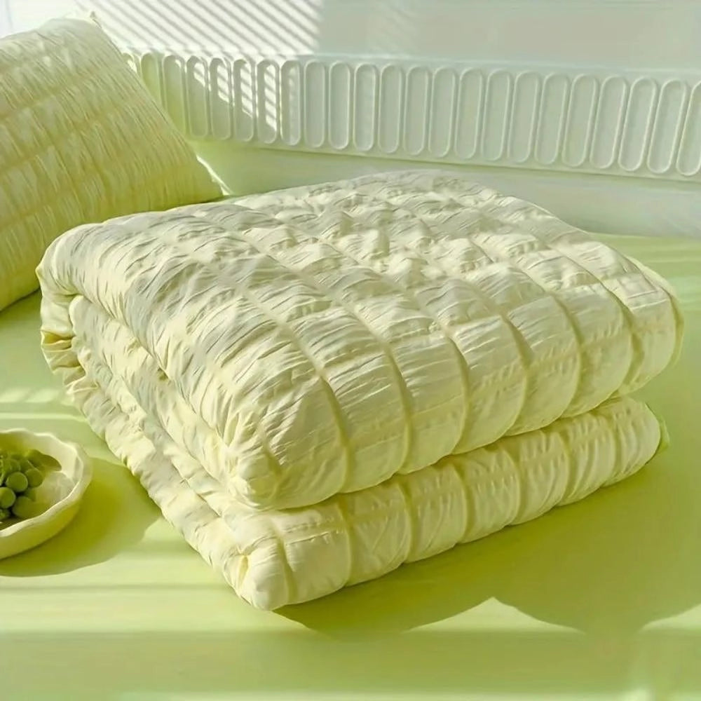A light blue ruffled comforter set displayed on a bed, showcasing its plush and textured design. The comforter is adorned with elegant ruffles, contributing to a luxurious and comfortable appearance. Two matching pillows are arranged neatly on the bed, enhancing the overall aesthetic and comfort of the bedding ensemble.