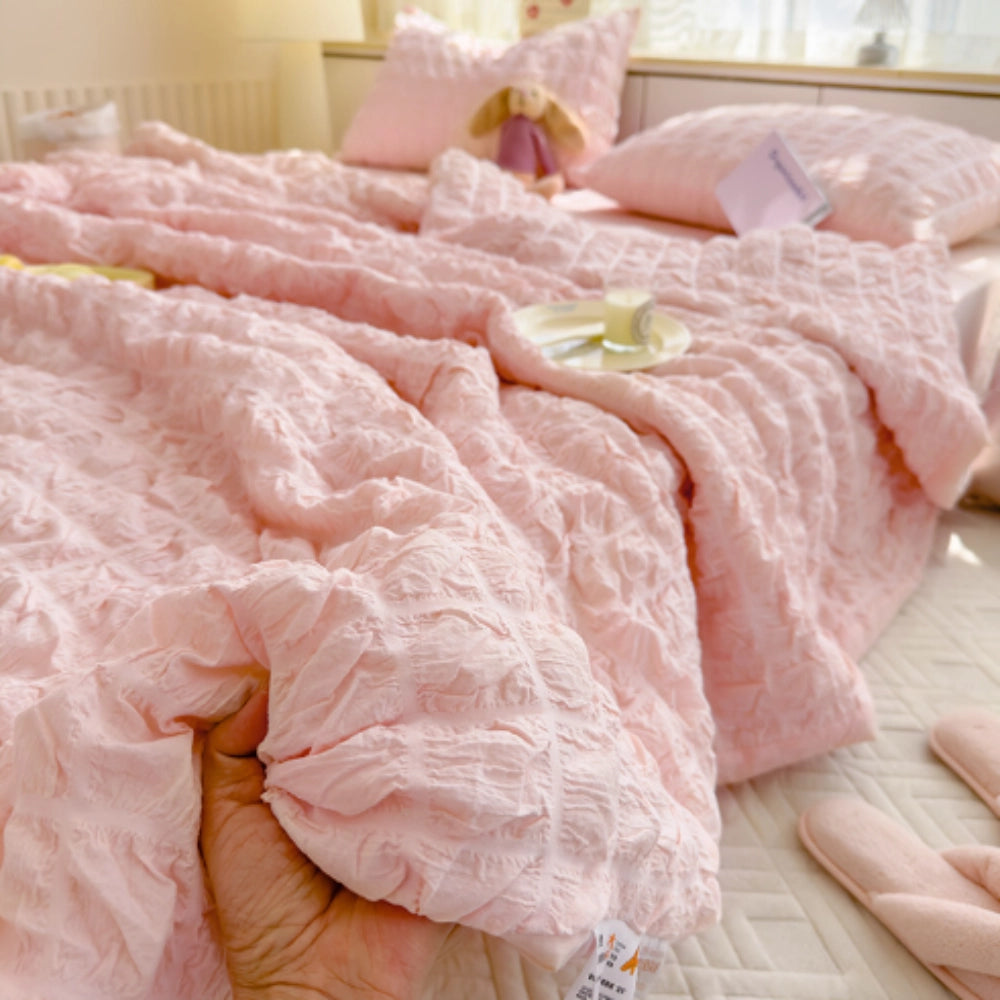 Luxurious light blue ruffled comforter set displayed on a bed, featuring a plush, textured design. The set includes a comforter and two matching pillowcases in a soft pink hue, elegantly complementing the bedding. The comforter measures 200x230cm, offering both comfort and style for a cozy bedroom ambiance.