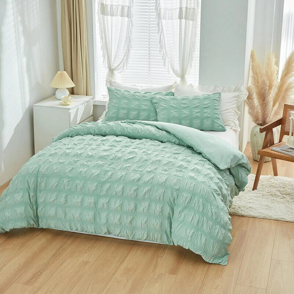 Light blue ruffled comforter set displayed on a bed with a wooden frame, featuring plush and textured bedding, accompanied by matching pillows in a cozy, well-designed interior space.