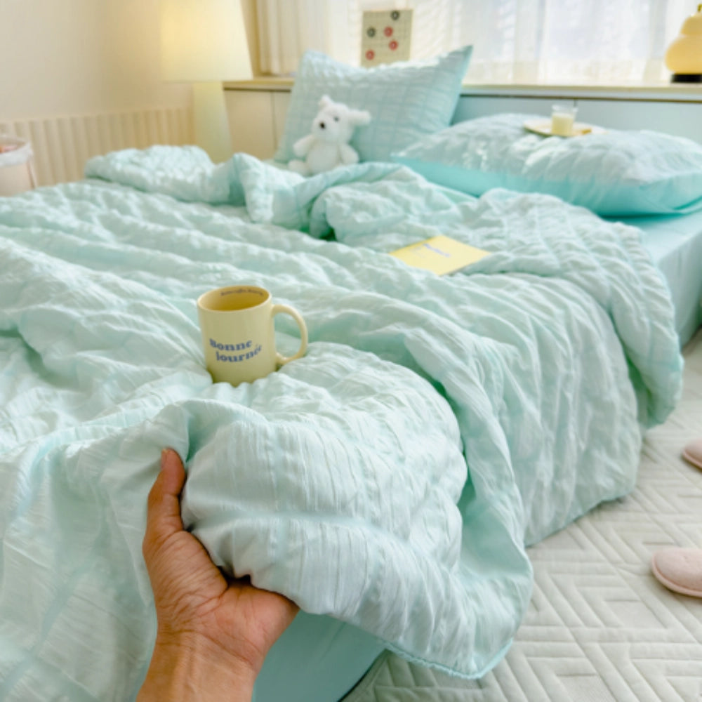 Light blue ruffled comforter set in ocean blue, displayed on a bed with a matching pair of pillowcases, showcasing its luxury plush texture and soft, inviting appearance.