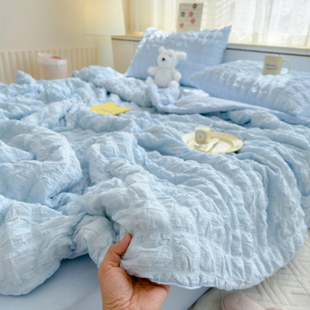 Sky blue ruffled comforter set with a plush, textured design, shown on a bed with matching pillowcases in a cozy bedroom setting.